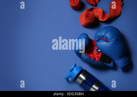 Boxhandschuhe mit Armbändern und Flasche Wasser auf blauem Hintergrund Stockfoto