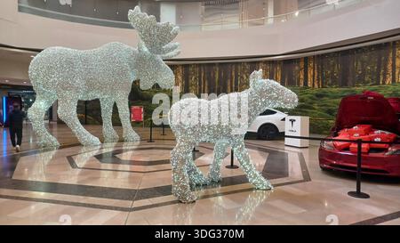 Toronto, ON, Kanada - 5. Januar 2026: Zwei funkelnde Tierstatuen stehen neben Elektroautos in einem geräumigen Einkaufszentrum. Stockfoto
