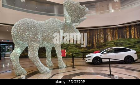 Toronto, ON, Kanada - 5. Januar 2026: Zwei funkelnde Tierstatuen stehen neben Elektroautos in einem geräumigen Einkaufszentrum. Stockfoto