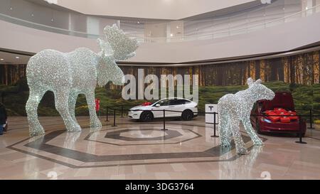 Toronto, ON, Kanada - 5. Januar 2026: Zwei funkelnde Tierstatuen stehen neben Elektroautos in einem geräumigen Einkaufszentrum. Stockfoto