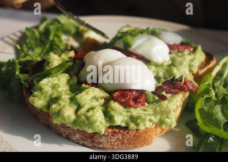 Frühstücksgericht mit Avocado, Eiern und Gemüse auf Toast Stockfoto