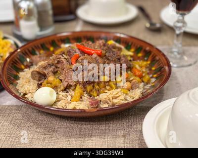Traditionelles usbekisches Plov mit Rindfleisch, Reis und Kichererbsen, serviert in einer Keramikschale Stockfoto