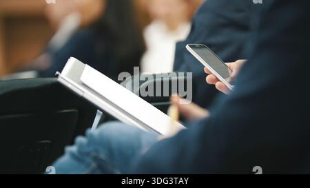 Man Mitarbeiter in Suit verwendet digitale Gerät sitzen auf dem Forum über Industrie und Wirtschaft Stockfoto