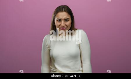 Frau, die verschiedene Emotionen vor einer isolierten rosafarbenen Hintergrundwand ausdrückt, die eine Reihe von Gesichtsausdrücken zeigt, einschließlich Verwirrung und Frustrat Stockfoto