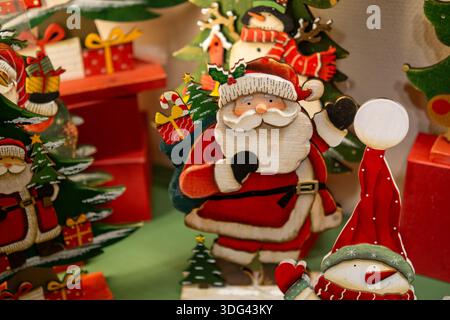 Handgemalte Weihnachtsmann- und Schneemannfiguren aus Holz in einer farbenfrohen Weihnachtsausstellung mit Geschenken und Bäumen. Stockfoto