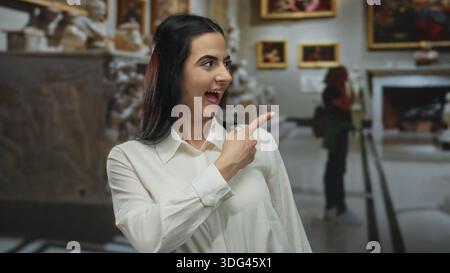 Die Frau zeigt aufgeregt in der Kirche, trägt ein weißes Hemd mit Kunsthintergrund und hebt die hispanische Kultur im Innenbereich hervor. Stockfoto