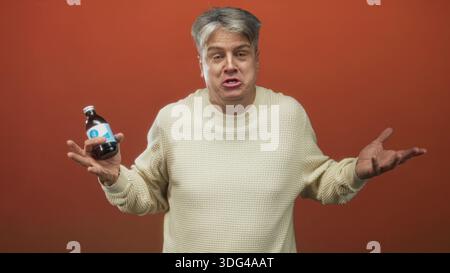 Mann mittleren Alters, der eine Arzneiflasche mit beiden Händen hält, mit offenen Händen zuckte Geste und sichtbare Handflächen in Richtung Kamera im Studio; Zweifel an Skepsis. Stockfoto