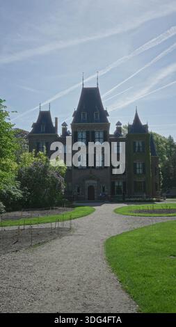 Das historische Schloss in keukenhof niederlande erhebt sich majestätisch mit seinen hohen Türmen und üppigen Gärten unter einem klaren blauen Himmel und bietet einen Blick auf niederländisch Stockfoto