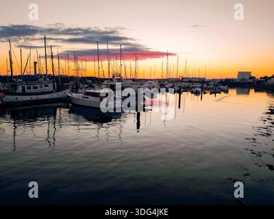 Erleben Sie Ruhe bei diesem Sonnenuntergang im goldenen Hafen mit Yachten, die in ruhigem Wasser vertäut sind. Der lebendige Horizont weckt Freiheit und Luxus, perfekt für Stockfoto