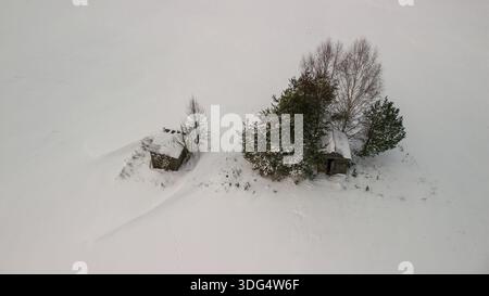 Blick von oben auf zwei verlassene Holzhütten in tiefem Schnee, Winterlandschaft Stockfoto