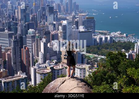 Hong Kong Stadtbild mit Victoria Harbour. Sonniger Blick auf die Stadt vom Braemar Hill. Frau, die Fotos von Hongkong macht. Stockfoto