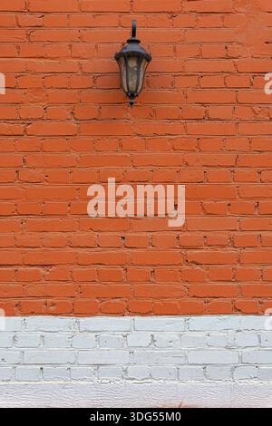 Dekorative Retro-Laterne an einer roten Ziegelwand. Unten befindet sich ein Streifen weißer Farbe. Stockfoto