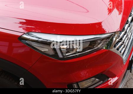 Nahaufnahme eines modernen roten Autoscheinwerfers mit Chromdetails Stockfoto