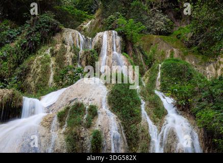 Die Erawan Falls stürzen sich in felsiges Gelände im Erawan National Park. Üppig grüner Wald umgibt den mehrstufigen Wasserfall. Stockfoto