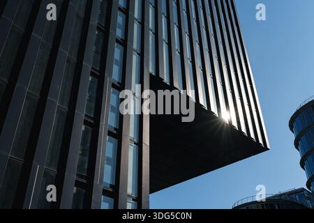 Hohes schwarzes, modernes Bürogebäude mit vertikalen Linien, die in klaren blauen Himmel ragen Stockfoto
