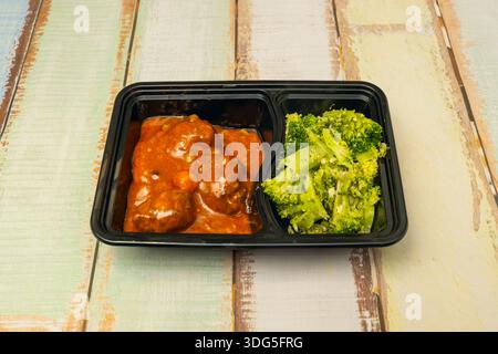 Hähnchenfleischbällchen in einer cremigen Pilzsauce, serviert mit gekochtem weißem Reis auf der Seite, mit zwei unterschiedlichen Farben auf demselben Teller Stockfoto