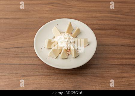 Nahaufnahme des Schüsselrandes, an dem das Eis auf eine flüssige Topping trifft, wobei die Tropfmuster und die scheinbare Viskosität des Sirups dokumentiert werden; Stockfoto