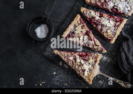 Kirsch- und Mandel-Streuseltorte, schwarzer Hintergrund, Draufsicht Stockfoto