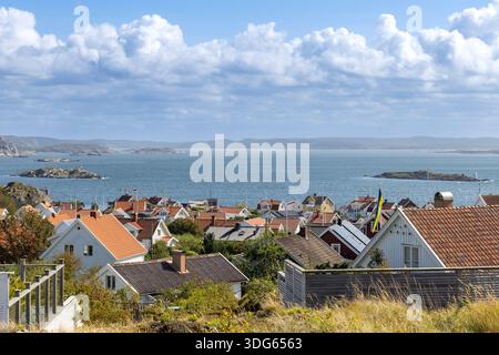 Hoher Blick auf die Insel Stora Dyron an der Küste von Tjorn, Schweden, mit roten Ziegeldächern, weißen Häusern, umgeben vom Meer, unter einer klaren blauen Ske Stockfoto