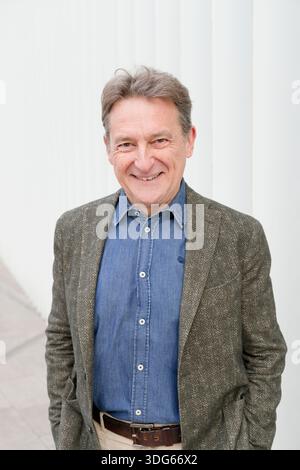 Lächelnder Mann in Denim-Hemd und strukturiertem Blazer vor weißem Hintergrund Italien Stockfoto