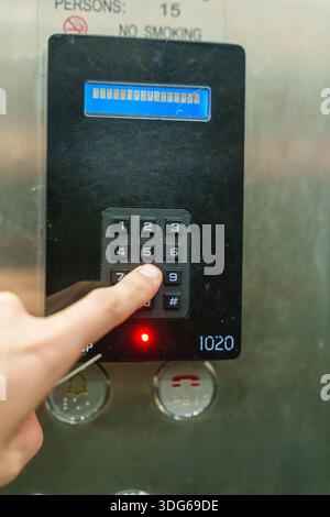 Person, die die Tastatur im Aufzug drückt, mit Bodenanzeige und Ladeinformationen Stockfoto