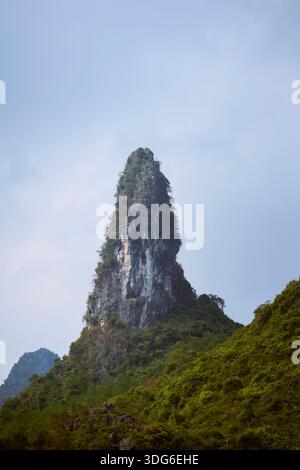 Scharfer, hoher Berggipfel bedeckt mit grünem Laub unter einem klaren Himmel Li-Fluss, Li Jiang, Guangxi, China Stockfoto