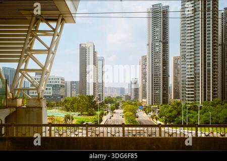 Städtische Skyline mit hohen Wolkenkratzern und einer Straße, die bei Tageslicht von grünen Bäumen gesäumt ist. Guangzhou, Guangdong, China Stockfoto