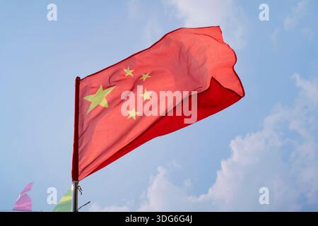 Chinesische Flagge winkt vor einem klaren blauen Himmel mit weißen Wolken im Hintergrund. Ausflug von Guilin nach Chengdu, Guangxi, Sichuan, China Stockfoto