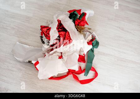 Glänzendes Geschenkpapier auf dem Boden verstreut, Umweltreinigung, Einzelhandelsabfall oder Feiertagsfeier enden Stockfoto
