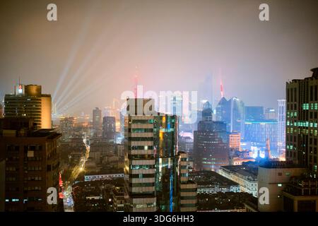 Skyline der Stadt bei Nacht mit bunten Lichtern und leuchtenden Gebäuden unter einem nebeligen Himmel. Shanghai, China Stockfoto