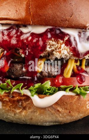 Ultra-Nahaufnahme eines saftigen Burgers mit Schichten Rindfleisch, geschmolzenem Käse, frischem Gemüse und einem gerösteten Brötchen, gekrönt mit einem dicken Deckel VI Stockfoto