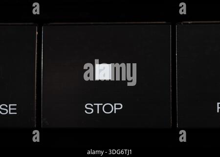 Nahaufnahme einer schwarzen Tastaturtaste mit der Bezeichnung STOP mit einem kleinen weißen Quadrat. Dieses Bild vermittelt Vorsicht, Pause und Kontrolle, ideal für die Sicherheit Stockfoto