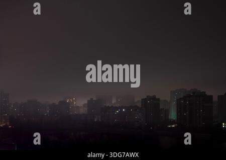 Kiew, Ukraine – 16. Januar 2023: Totaler Stromausfall im Wohnschlafgebiet Kiews. Blick aus einem hohen Winkel auf dunkle Gebäudesilhouetten in der Nähe des Sonyachne Lake. Stockfoto