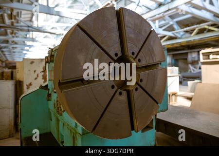 Nahaufnahme eines großen runden Metallfutters auf einer industriellen Drehmaschine. Professionelle Ausrüstung für die Schwerfertigung und Verarbeitung von Metallkomponenten. De Stockfoto