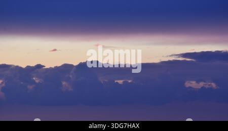 Ein ruhiger und romantischer Abendhimmel mit einem glatten violetten Farbverlauf und zarten, rosa Wolken in einer friedlichen Atmosphäre. Stockfoto