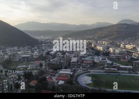 Aus der Vogelperspektive auf eine Landschaft, in der sich die Gebäude der Gerberfabrik zwischen den Hügeln schmiegen, mit einem Stadion, das der Szene einen lebhaften grünen Touch verleiht, Solofra, Stockfoto