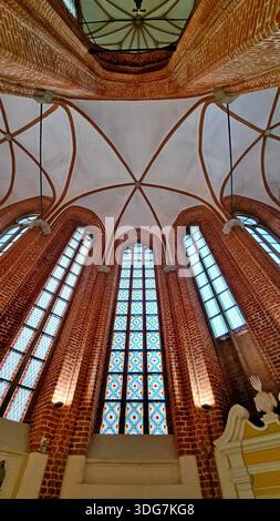 Gotisches Interieur der Peterskirche mit Spitzbögen, gerippten Gewölben und Buntglasfenstern mit komplexen geometrischen Mustern. Riga, Lettland Stockfoto
