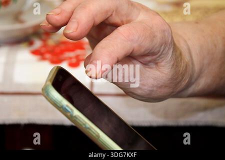 Hand eines älteren Mannes und Smartphone. Stockfoto