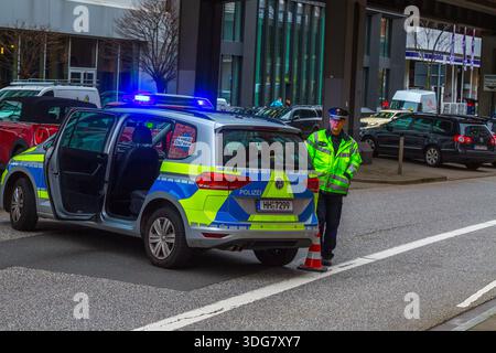 Hamburg, Deutschland – 21. Februar 2020: Polizeibeamter steht freitags für Fut neben einem Streifenwagen mit offener Hintertürblockstraße bei Baumwall Stockfoto