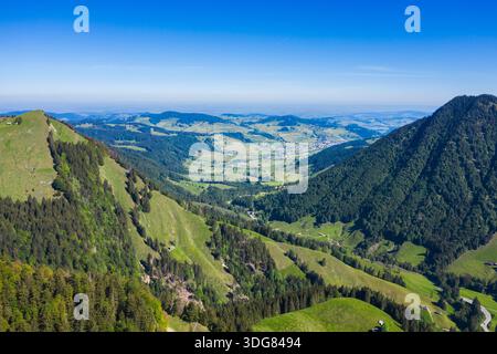 Ein weicher Blick aus der Luft fängt den üppigen, grünen Talboden ein, der zwischen sanften Hügeln in den Schweizer Alpen liegt und die atemberaubende Schönheit des Re zeigt Stockfoto