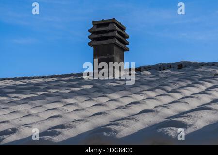Verstaubte Dachziegel mit Kamin nach Schneefall in Mugello, Italien Stockfoto