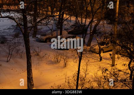 Der Winterhof eines mehrstöckigen Gebäudes in der Stadt Dnipro, Ukraine, Nacht und Fußspuren im Schnee und das Licht der Laternen, ruhiges Stadtatmo Stockfoto