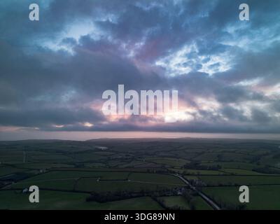 Dramatischer Sonnenuntergangshimmel mit Wolken über der ländlichen Landschaft, von oben in Cornwall, England Stockfoto