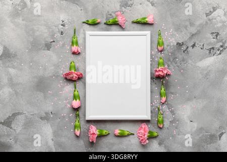 Leerer weißer Rahmen mit rosafarbenen Blumen auf grauem Marmorhintergrund Stockfoto
