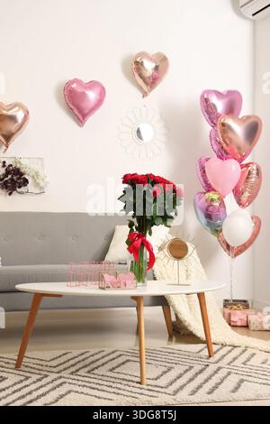 Das Innere des festlichen Wohnzimmers ist mit Ballons in Herzform und Rosenstrauß zum Valentinstag dekoriert Stockfoto