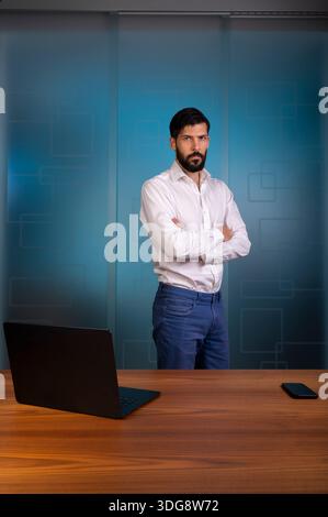 Mann, der in einem modernen Büro steht und ein Unternehmen oder ein Unternehmen repräsentiert, das ein weißes Hemd und eine blaue Hose trägt - Hosen Stockfoto