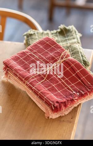 Eine Nahaufnahme gefalteter rot-grün karierter Leinenservietten, die mit natürlichem Jutegarn ordentlich gebunden sind. Stockfoto