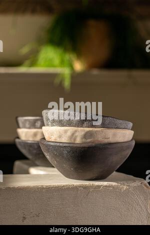 Eine minimalistische Komposition aus handwerklichen Schalen aus Steingut, die auf einem Steinvorsprung angeordnet sind, mit rustikalen Texturen und organischen Glasuren in Anthrazit-Schwarz. Stockfoto