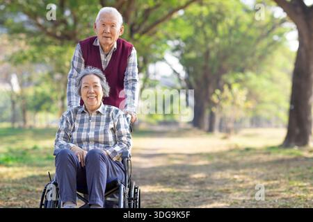 Asiatische ältere oder ältere Frau Patientin im Rollstuhl im Park Stockfoto