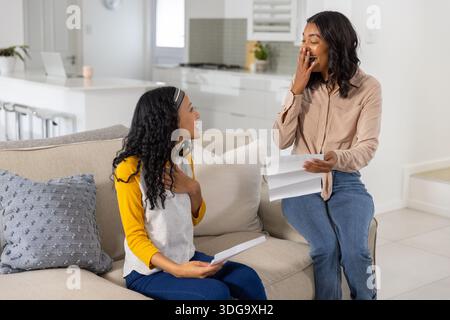 Verschiedene Eltern und Teenager-Tochter lesen Briefe, während sie auf beigefarbenem Sofa sitzen Stockfoto